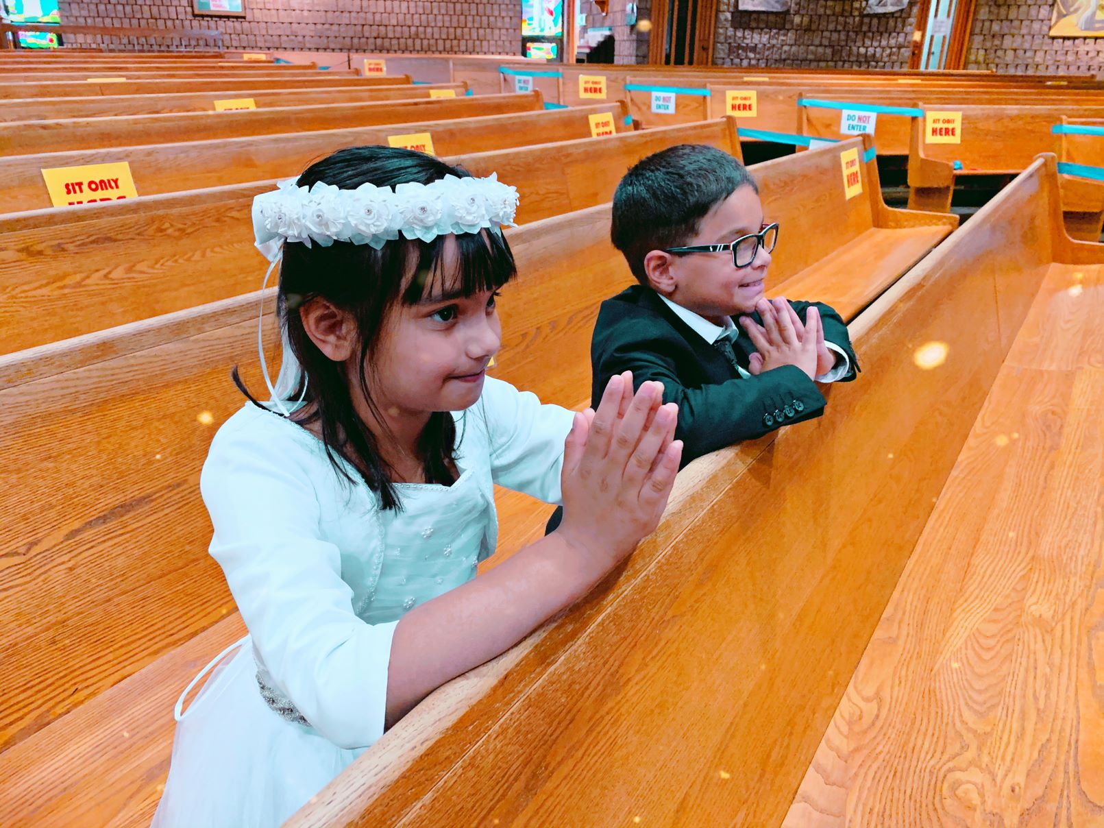 Communion students, boy and a girl, kneeling in the pews